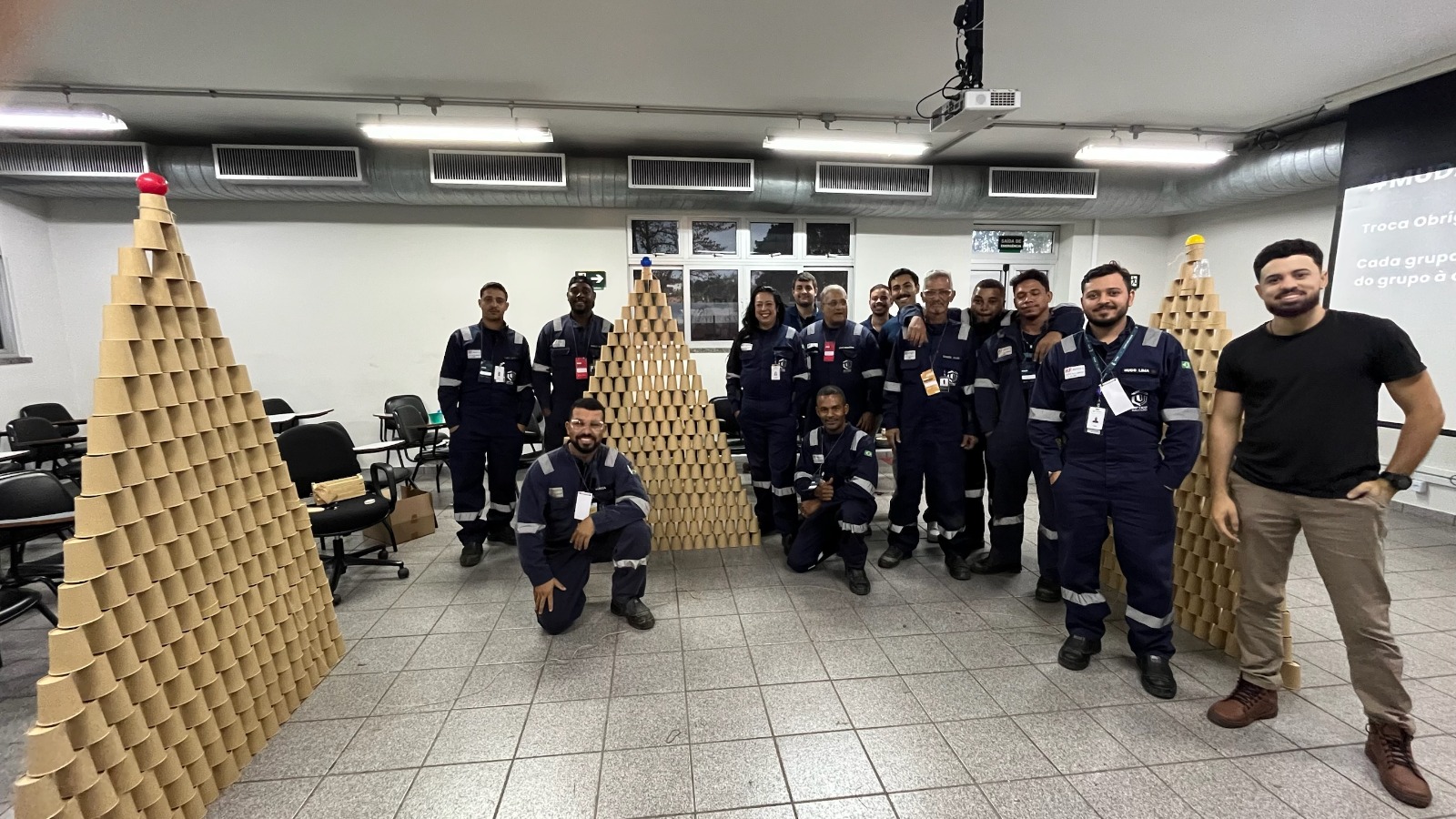 Equipe celebrando o resultado de uma atividade em grupo com pirâmides de copos
